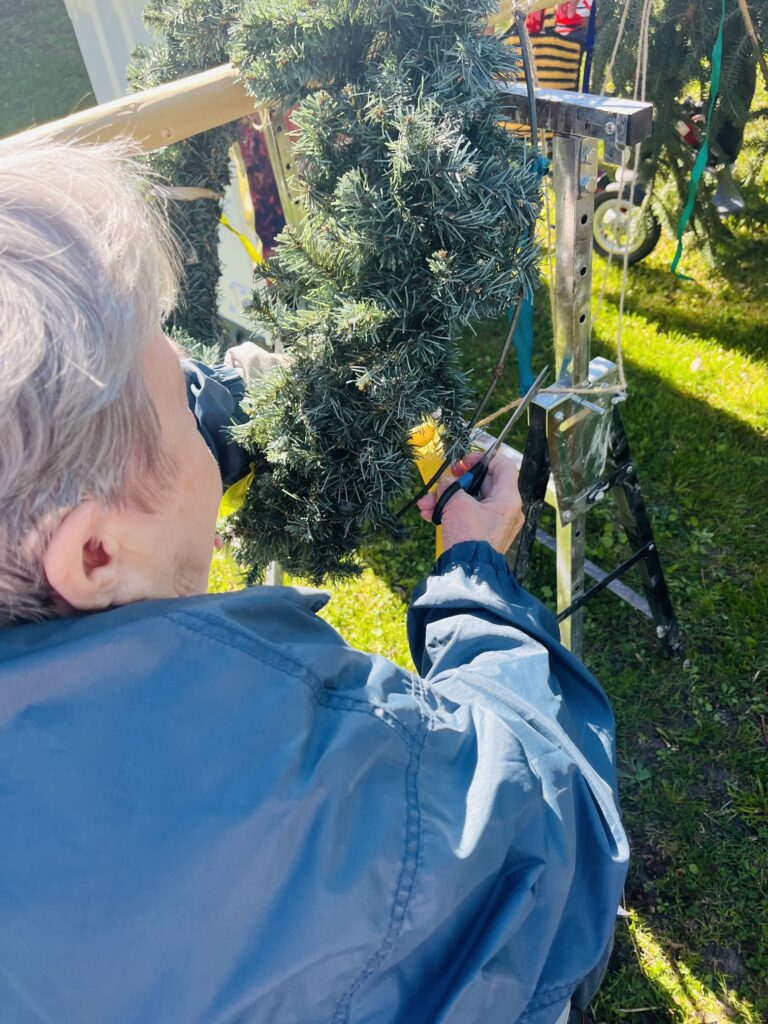 Klientka zdobí špičku májky krepovým papírem