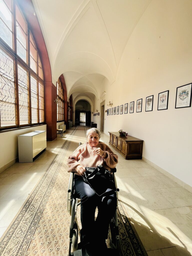 Klientka na vozíku v chodbě zámku