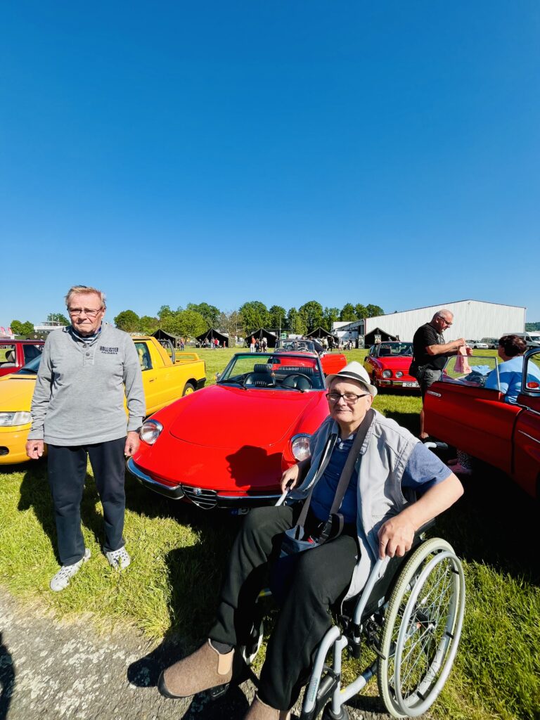 Dva klienti pózují u historických automobilů