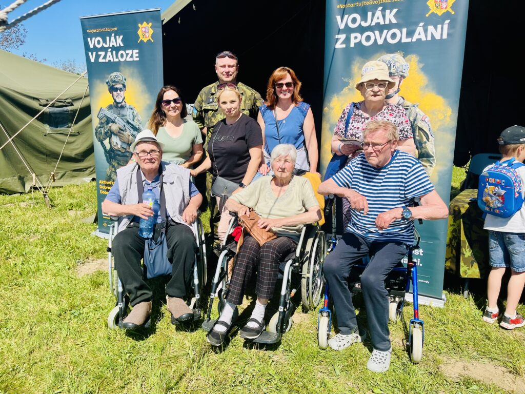 Klienti a zaměstnanci pózují s vojákem před stanem