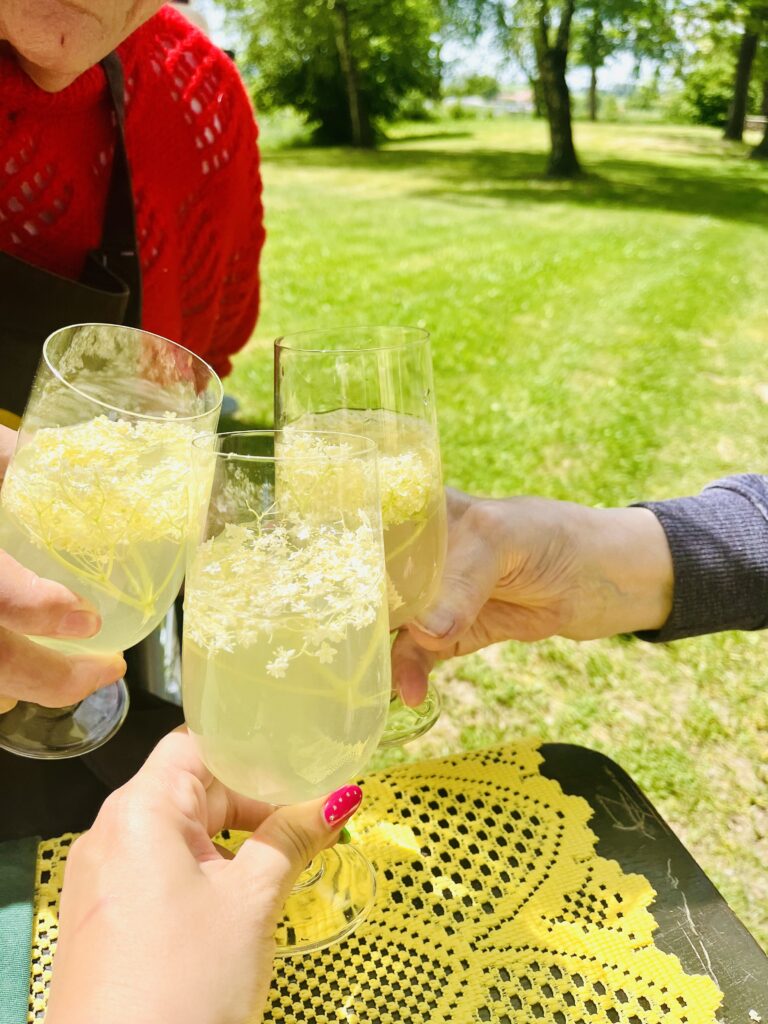 Tři ruce drží sklenky s limonádou z černého bezu a společně si připíjí