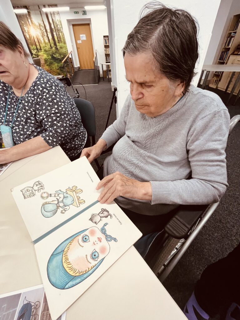 Klientka prohlíží knihu s nádhernými ilustracemi Heleny Zmatlíkové