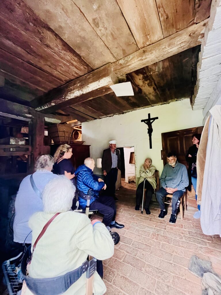 Klienti sedí v dobové světnici a poslouchají výklad pana mlynáře