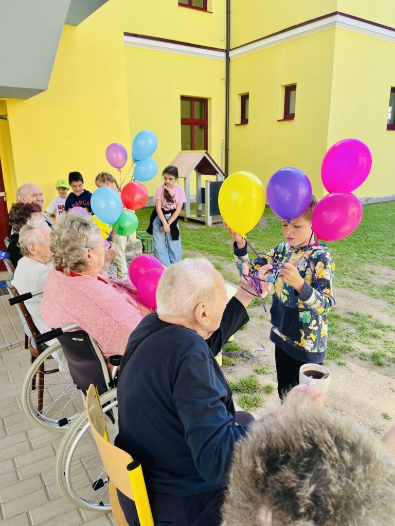 Klienti našeho domova obdarovávají děti balónky