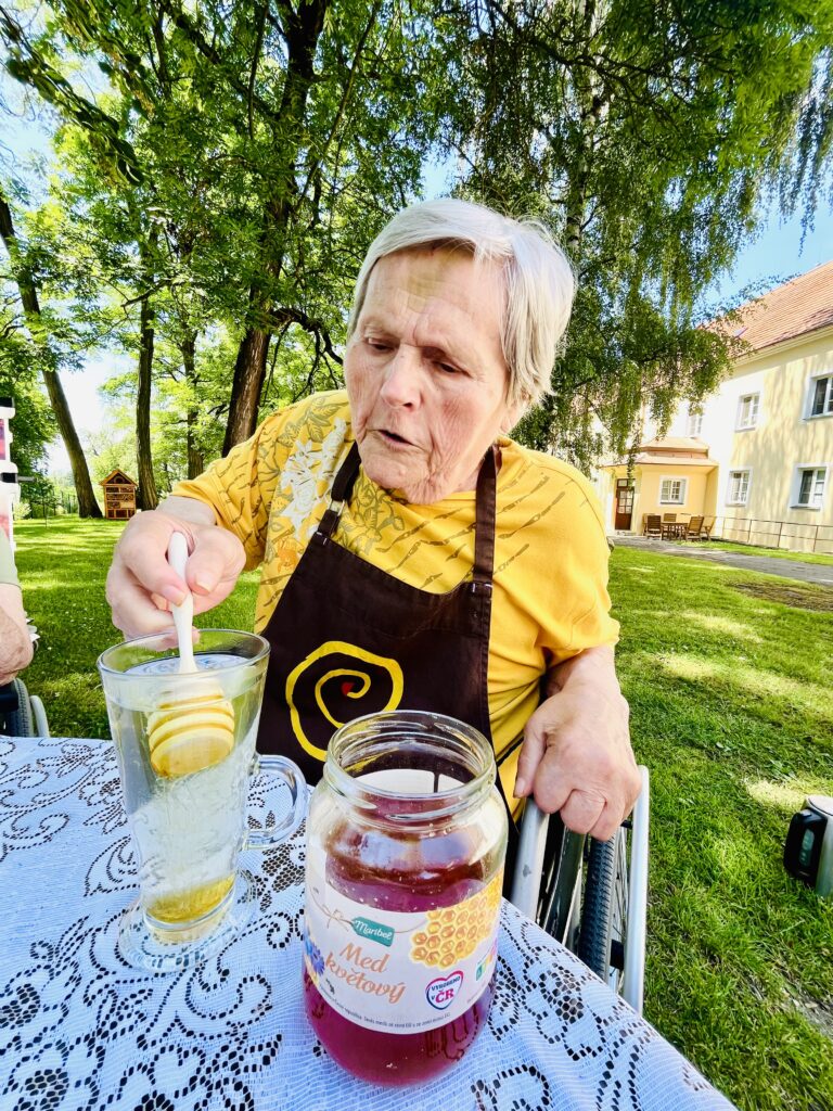 Klientka si sladí medem vylouhovaný čaj