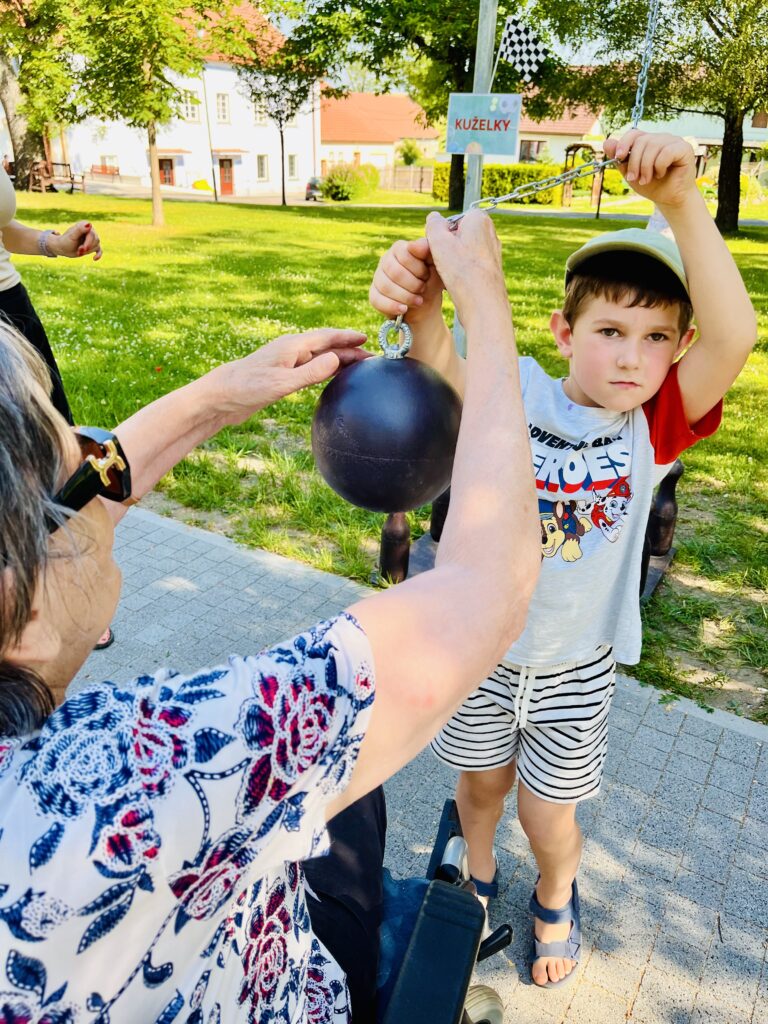 Chlapec -předškolák z MŠ Mirotice -podává kouli ke sražení kuželek klientce