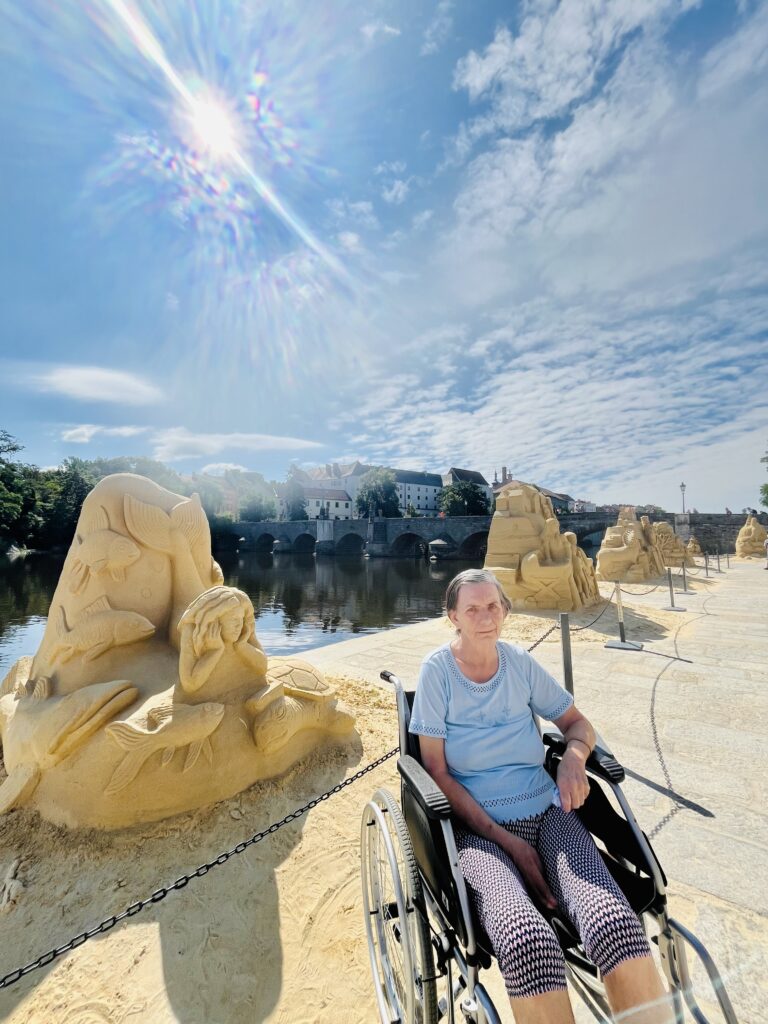 Klientka pózuje před sochou z písku
