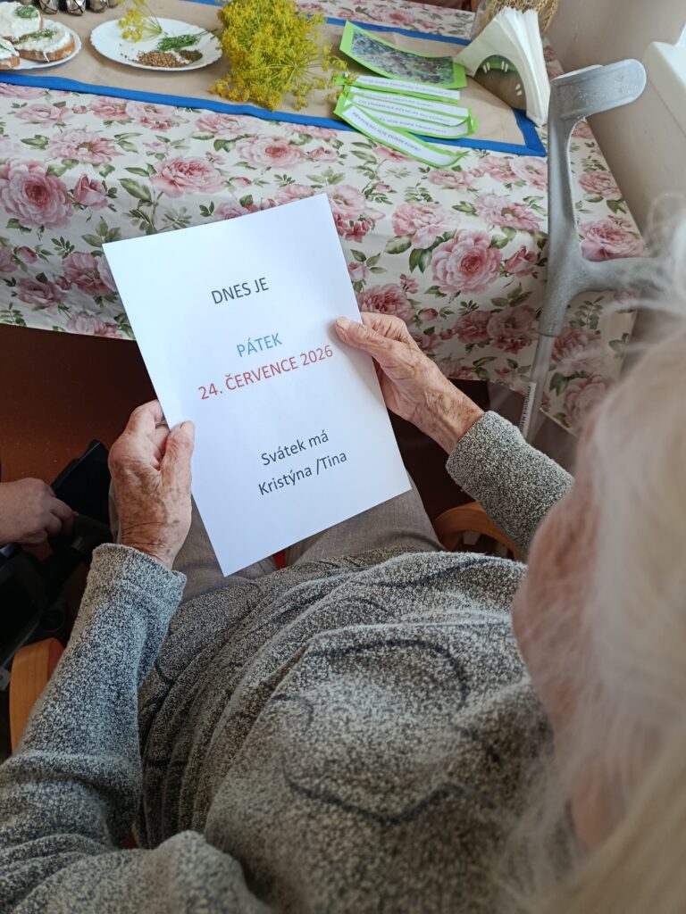 Klientka drží v rukou ceduli s aktuálním datema ročním obdobím