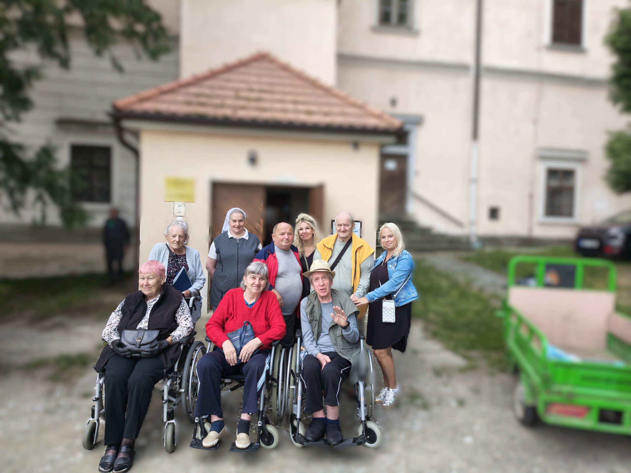 Klienti, aktivizační pracovnice pózují s řádovou sestrou u vchodu do zámku