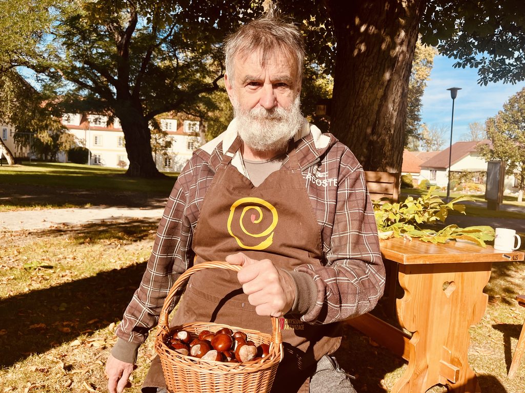 Klient sedí na lavičce s nasbíranými kaštany