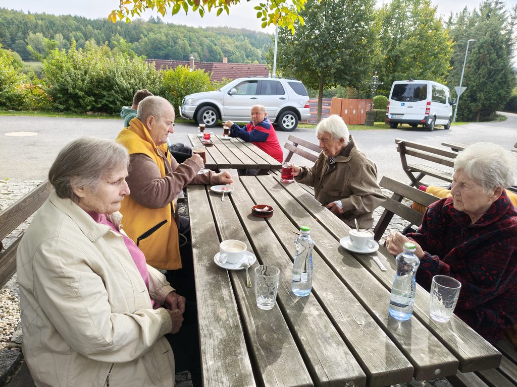 Klienti sedí v hostinci U Báby Lišků a pijí kávu
